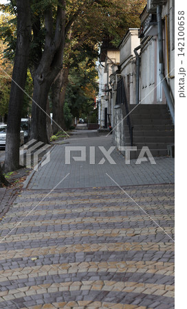 Quiet sidewalk scene in a city during autumn. Quiet sidewalk scene in a city during autumn. 142100658