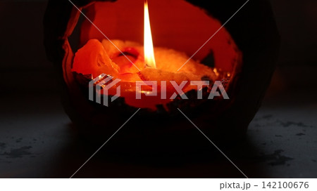 A burning candle in a candlestick. 142100676