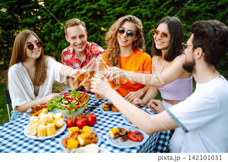 Happy friends in picnic in park. Friends grill meat, have fun, relax. ?oncept of holidays, weekends. Happy friends in picnic in park. Friends grill meat, have fun, relax. ?oncept of holidays, weekends. 142101031