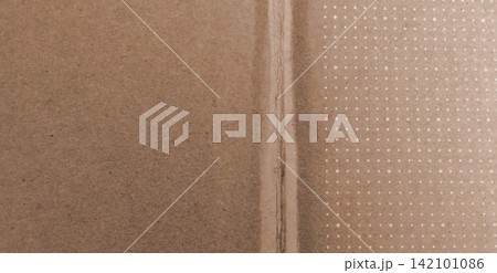 Textured brown cardboard with fold lines and a white dot pattern. Textured brown cardboard with fold lines and a white dot pattern. 142101086