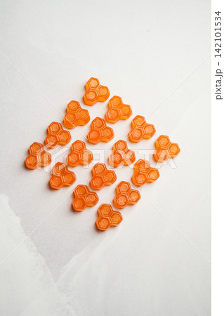 Orange vitamins jelly gummies on bright background, food supplements, top view Orange vitamins jelly gummies on bright background, food supplements, top view 142101534