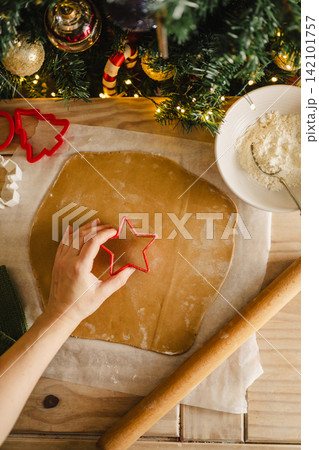 Holiday background. Rolling pin, female hands and raw rolled dough, cooking Christmas gingerbread cookies. Top view Holiday background. Rolling pin, female hands and raw rolled dough, cooking Christmas gingerbread cookies. Top view 142101757