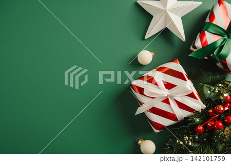 Christmas flat lay frame, composition with gifts boxes and festive stars, baubles over green background 142101759