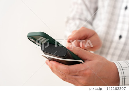 充電しながらスマートフォンを操作する男性 142102207