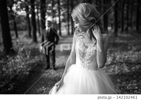 Black and white photo of Beautiful bride in white dress for walk in park. Wedding day. Fashion bride 142102461