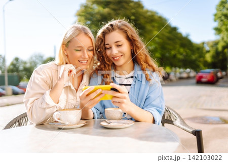Smiling woman are sitting in a cafe, taking selfies, talking with friends. Fashion, beauty. Smiling woman are sitting in a cafe, taking selfies, talking with friends. Fashion, beauty. 142103022