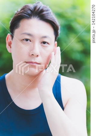 屋外で真剣に片手で頬をケアする40代男性のボタニカルスキンケア 屋外で真剣に片手で頬をケアする40代男性のボタニカルスキンケア 142104270