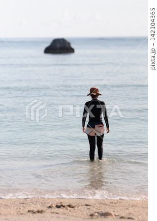 穏やかな浅瀬の海に立つ女性の後ろ姿 穏やかな浅瀬の海に立つ女性の後ろ姿 142104365