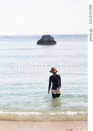 晴れた日に穏やかな海へ歩いて入る女性の後ろ姿 142104366