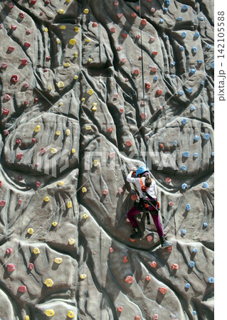 girl climbs a big rock wall at the gym girl climbs a big rock wall at the gym 142105588