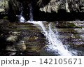 Waterfall Cascading Over Layered Rocks in Forest 142105671