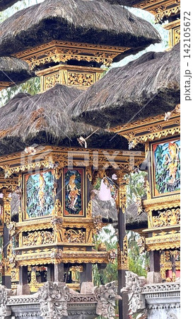 Balinese Hindu temple shrines presenting ornate golden carvings, colorful relief art, and traditional thatched roofs, reflecting rich cultural heritage and religious devotion 142105672