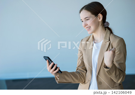 Young woman celebrating success looking at mobile phone Young woman celebrating success looking at mobile phone 142106049