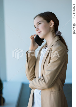 Young businesswoman talking on smartphone in office building Young businesswoman talking on smartphone in office building 142106071
