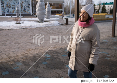 Pregnant woman walking outdoors in winter park wearing warm coat and knitted hat Pregnant woman walking outdoors in winter park wearing warm coat and knitted hat 142106122