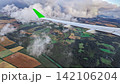 Scenic aerial view from airplane window during daytime flight, with aircraft wing, patchwork fields and forest landscape 142106204