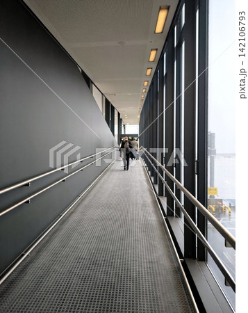 A long ramp with glass walls in the airport terminal 142106793