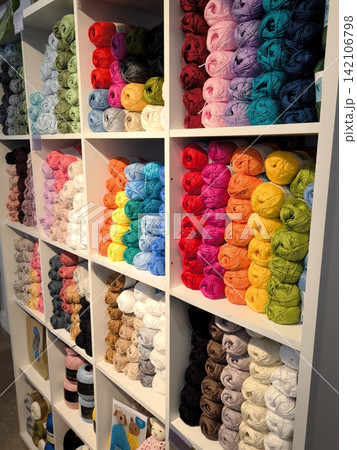 Multicolored skeins of yarn for handicrafts on the shelves in a craft store. 142106798