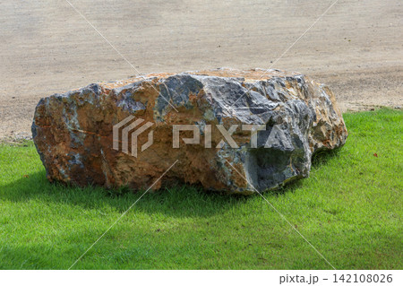 Large Natural Boulder with Orange and Grey Mineral Texture on Green Lawn Large Natural Boulder with Orange and Grey Mineral Texture on Green Lawn 142108026