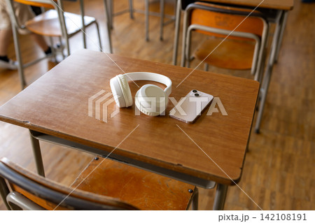 学校の机に置かれたスマホとヘッドホン 142108191