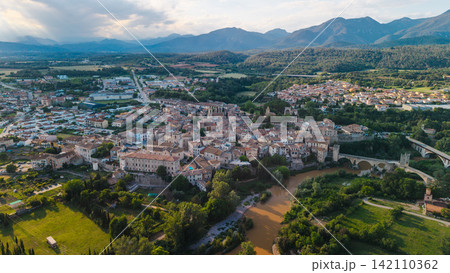 Aerial panoramic view of Besalu medieval town and historic stone bridge in Catalonia Spain surrounded by mountains and green countryside at sunset 142110362