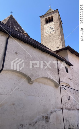 Interior of a small traditional alpine chapel with benches and fresh water tank for travelers 142111108