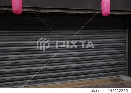 シャッターが降りている店舗。閉店や休業のイメージ。金属製シャッター。 シャッターが降りている店舗。閉店や休業のイメージ。金属製シャッター。 142112236