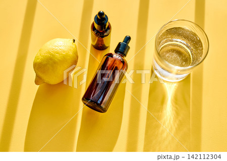 Citrus essential oil bottles with fresh lemon and water 142112304