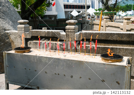Row of burning red chinese ritual candles at an outdoor incense altar area of the historic A-Ma Temple in macau 142113132