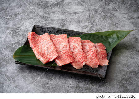 お皿に載せたサシの入った国産黒毛和牛のモモ肉(トモサンカク)のスライス お皿に載せたサシの入った国産黒毛和牛のモモ肉(トモサンカク)のスライス 142113226