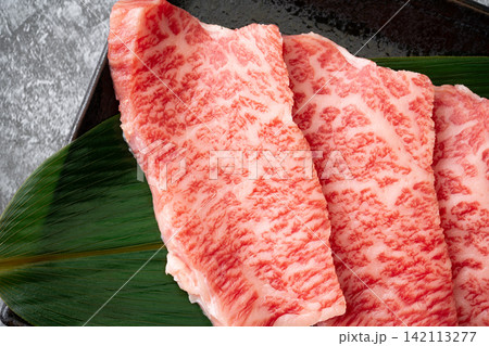 サシの入った国産黒毛和牛のモモ肉(トモサンカク)のスライスのクローズアップ サシの入った国産黒毛和牛のモモ肉(トモサンカク)のスライスのクローズアップ 142113277