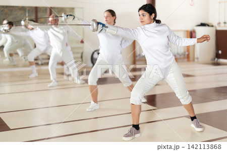 Men and women practicing epee moves in gym 142113868