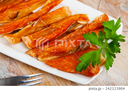 Smoked salmon belly strips on plate on wooden table Smoked salmon belly strips on plate on wooden table 142113904