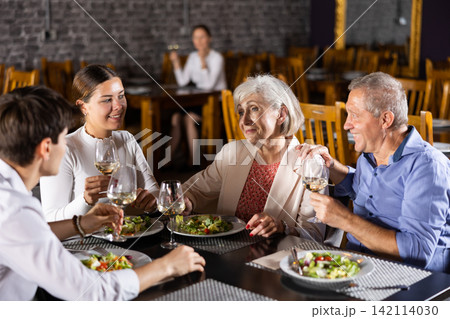 Senior parents enjoying dinner with adult children in restaurant 142114030