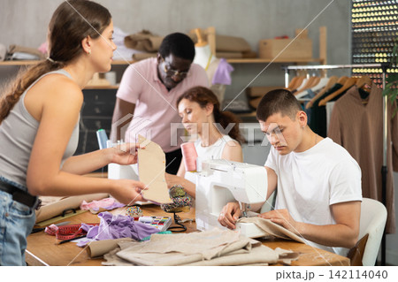 Engaged guy stitching fabric on machine in sewing class for adults Engaged guy stitching fabric on machine in sewing class for adults 142114040