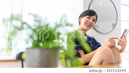 スマホを見て微笑む若い女性 スマホを見て微笑む若い女性 142114244