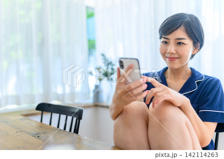 ルームウェアを着てスマホを見る女性 142114263