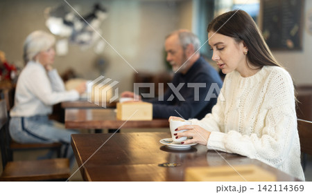 Pretty woman drinks coffee in cafe interior Pretty woman drinks coffee in cafe interior 142114369