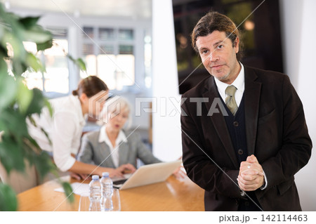Interested adult businessman in formal suit inviting to office 142114463