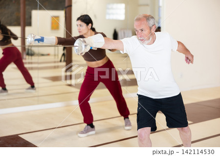 Elderly man attending fencing lessons Elderly man attending fencing lessons 142114530