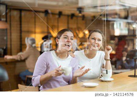 Smiling young female friends drinking coffee at cafe Smiling young female friends drinking coffee at cafe 142114576