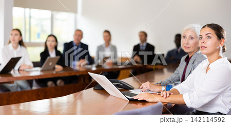 International group of business people listening to presentation at tables in meeting room International group of business people listening to presentation at tables in meeting room 142114592