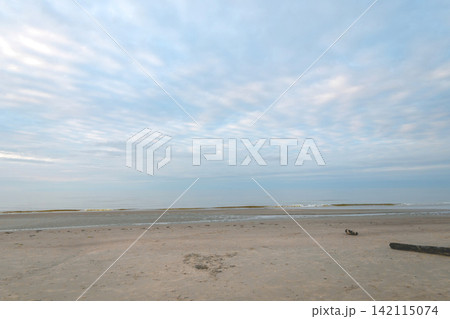Peaceful Seascape with Sandy Beach and Calm Sea Under blue cloudy Sky Peaceful Seascape with Sandy Beach and Calm Sea Under blue cloudy Sky 142115074