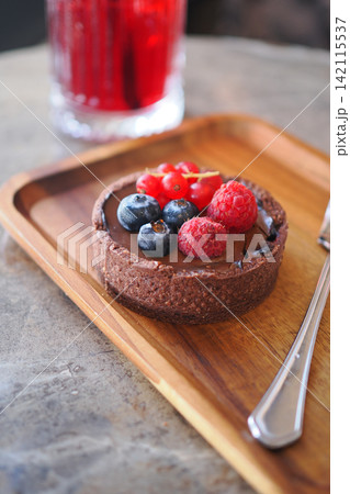 Chocolate tart with berries on wooden plate Chocolate tart with berries on wooden plate 142115537