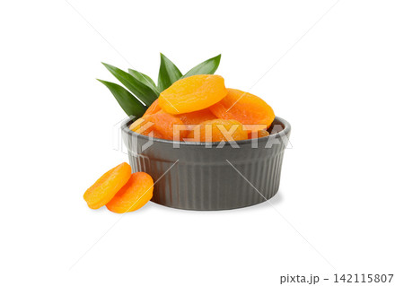 Bowl contains dried apricots with green leaves nearby, PNG 142115807