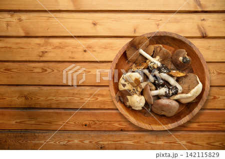Fall. Mushrooms rest in a wooden bowl on rustic table 142115829