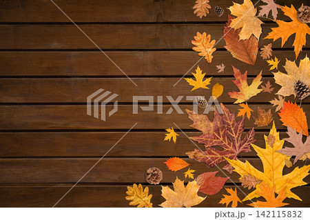 Autumn. Vibrant fall leaves and pine cones scattered on wooden surface 142115832