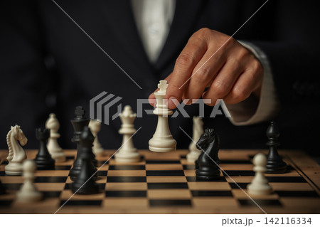 hand placing white chess king on wooden board, business strategy concept 142116334