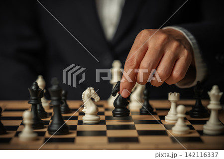 business hand moving a black chess knight and white facing off on board with multiple pieces business hand moving a black chess knight and white facing off on board with multiple pieces 142116337