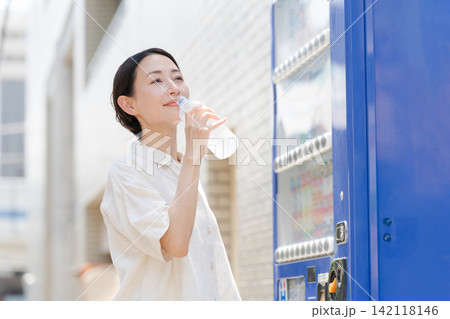 自販機で買った水を飲む女性 142118146
